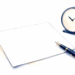 白い机の上に置かれた一枚の報告書と万年筆、傍らの置き時計を描いた紺色の水彩イラスト